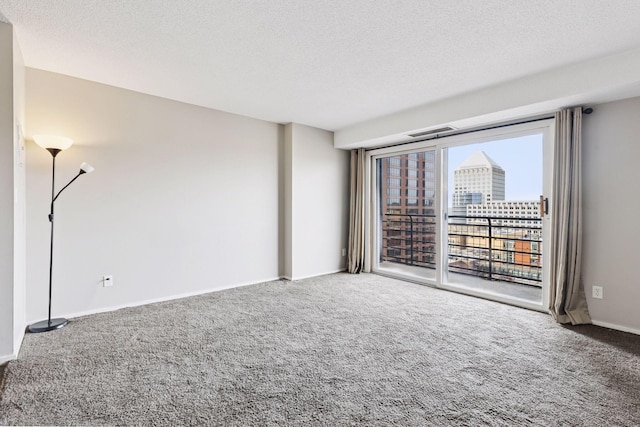 unfurnished room with a city view, a textured ceiling, and carpet floors