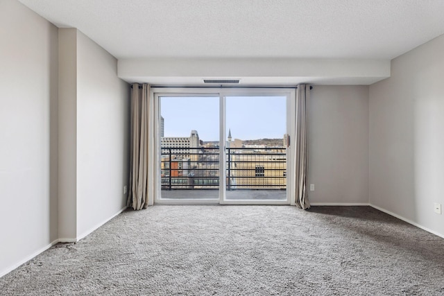 spare room featuring visible vents, baseboards, carpet floors, and a textured ceiling