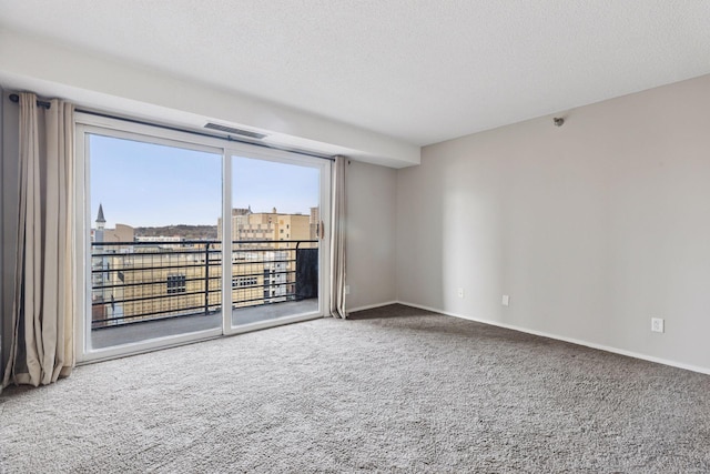 spare room featuring baseboards, carpet, visible vents, and a textured ceiling