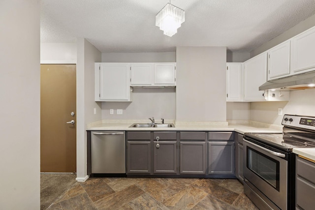kitchen with a sink, gray cabinetry, light countertops, under cabinet range hood, and appliances with stainless steel finishes