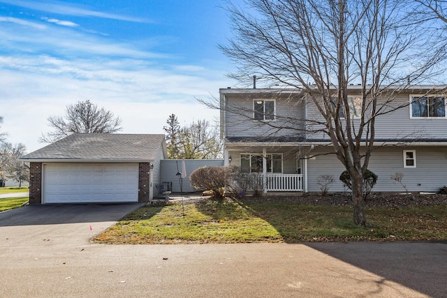 traditional-style home featuring a porch, a garage, brick siding, and aphalt driveway