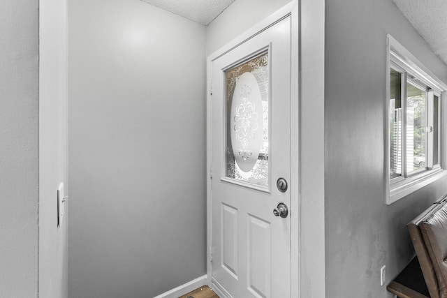 entryway featuring a textured ceiling and baseboards