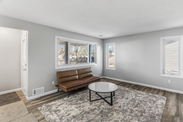 living room featuring visible vents, a textured ceiling, and wood finished floors