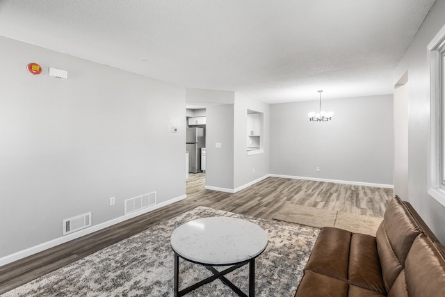 living area with visible vents, an inviting chandelier, and wood finished floors