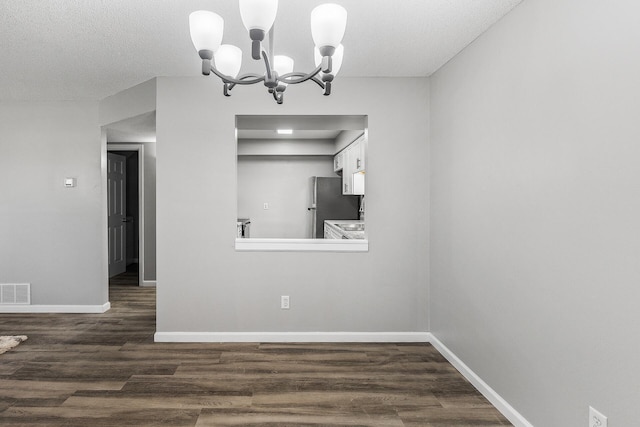 unfurnished dining area with a notable chandelier, visible vents, baseboards, and dark wood-style flooring