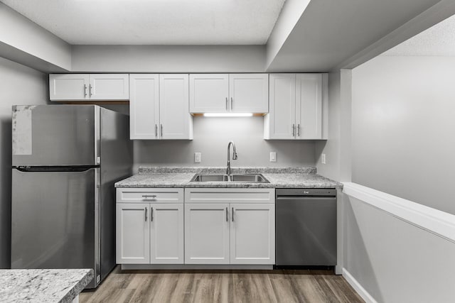 kitchen featuring light wood-style flooring, appliances with stainless steel finishes, white cabinetry, and a sink