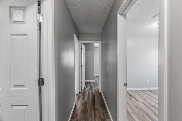 hall featuring dark wood finished floors, baseboards, and a textured ceiling