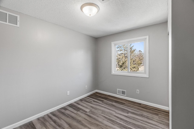 spare room featuring wood finished floors, baseboards, and visible vents