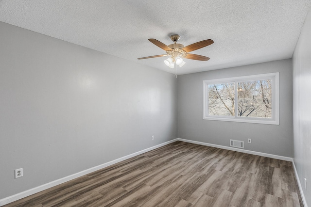 unfurnished room featuring visible vents, ceiling fan, baseboards, wood finished floors, and a textured ceiling