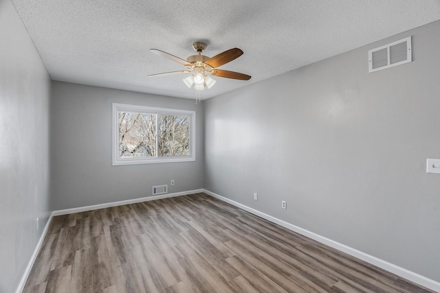 empty room featuring visible vents, baseboards, and wood finished floors