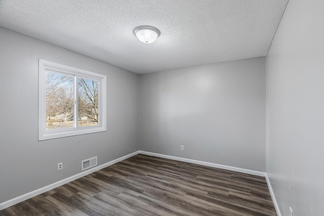 empty room featuring visible vents, baseboards, a textured ceiling, and dark wood finished floors