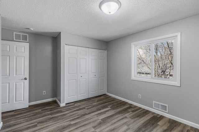 unfurnished bedroom with visible vents, baseboards, a closet, and wood finished floors