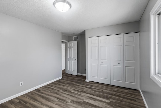 unfurnished bedroom featuring visible vents, baseboards, and dark wood-style floors