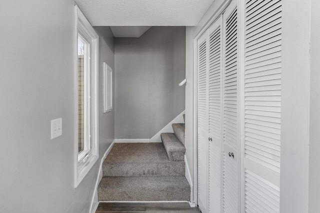 stairs featuring wood finished floors, baseboards, and a textured ceiling