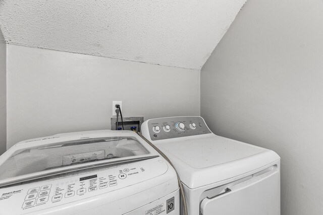 laundry area with washing machine and clothes dryer, laundry area, and a textured ceiling