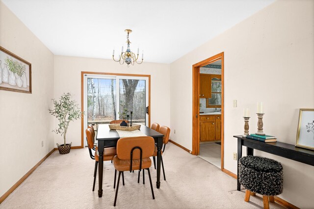 dining area featuring light colored carpet, baseboards, and a chandelier