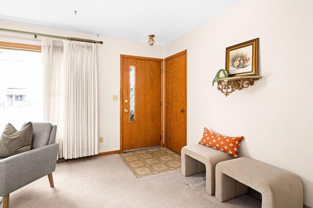 foyer entrance with baseboards and light colored carpet