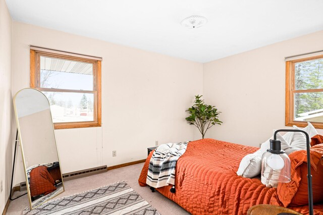 bedroom with a baseboard radiator, light colored carpet, and baseboards