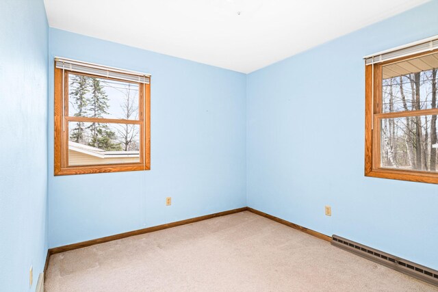 carpeted empty room with a baseboard radiator and baseboards
