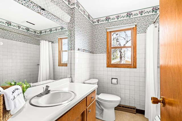 full bath featuring wallpapered walls, a wainscoted wall, a healthy amount of sunlight, and tile walls