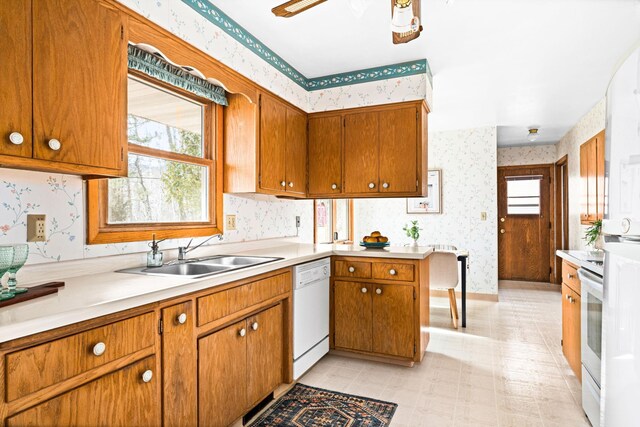 kitchen featuring white appliances, wallpapered walls, light countertops, and a sink