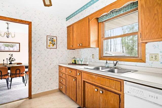 kitchen with a sink, wallpapered walls, light countertops, and dishwasher