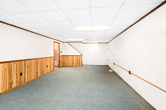 finished below grade area with a drop ceiling, a wainscoted wall, dark carpet, and wallpapered walls