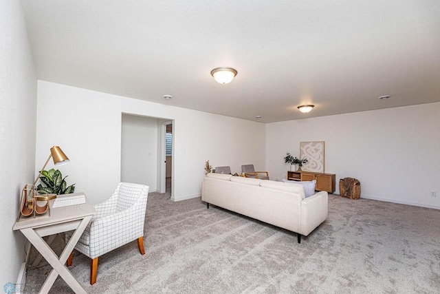 living area featuring light carpet and baseboards