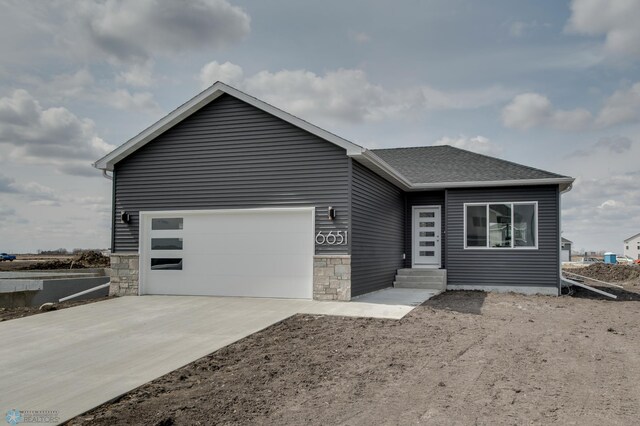 view of front facade with an attached garage, a shingled roof, stone siding, entry steps, and concrete driveway