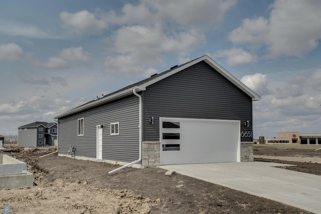 view of property exterior with a garage, driveway, and stone siding