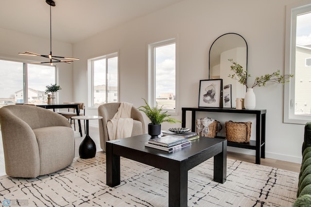 dining space with baseboards, a wealth of natural light, light wood-type flooring, and a chandelier