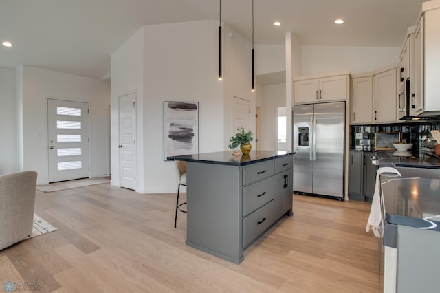 kitchen with dark countertops, appliances with stainless steel finishes, a breakfast bar area, a center island, and light wood-type flooring
