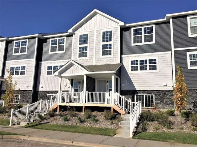 multi unit property featuring stairway, stone siding, board and batten siding, and a porch