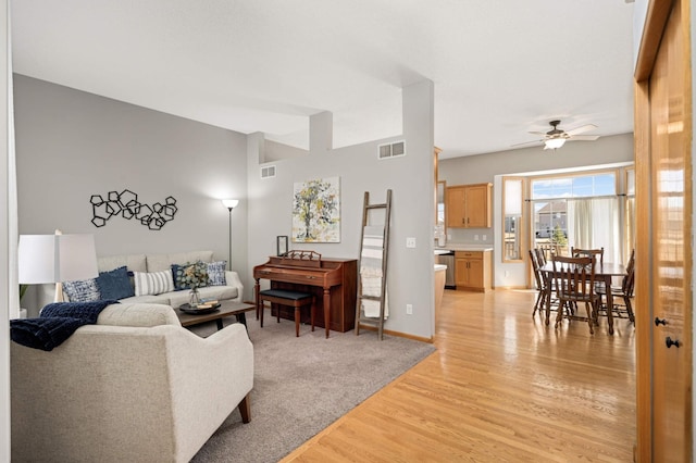 living area with visible vents, ceiling fan, baseboards, and light wood-style floors