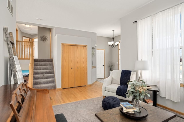 living area with visible vents, a notable chandelier, wood finished floors, stairway, and baseboards