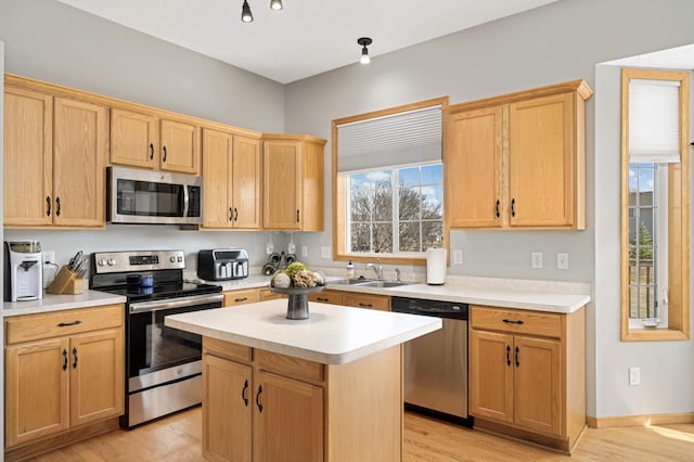 kitchen featuring a sink, a center island, light wood-style floors, appliances with stainless steel finishes, and light countertops