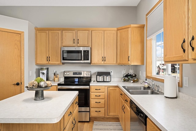 kitchen with light brown cabinets, a center island, light countertops, stainless steel appliances, and a sink