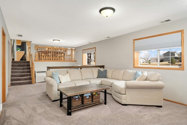 carpeted living area with stairs, baseboards, visible vents, and a textured ceiling