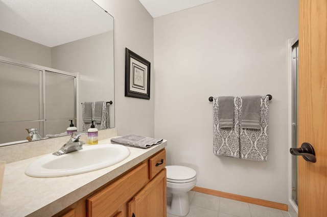 bathroom featuring tile patterned flooring, baseboards, toilet, a stall shower, and vanity