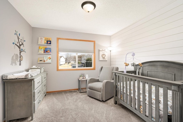 carpeted bedroom with baseboards, a nursery area, and a textured ceiling