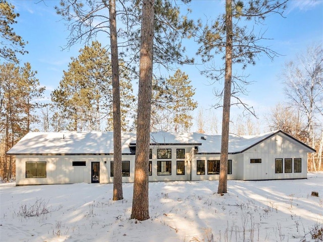 snow covered rear of property featuring board and batten siding