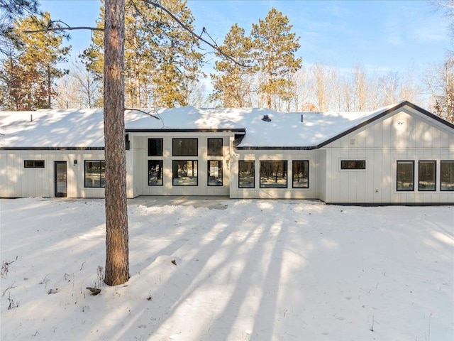 snow covered house featuring board and batten siding