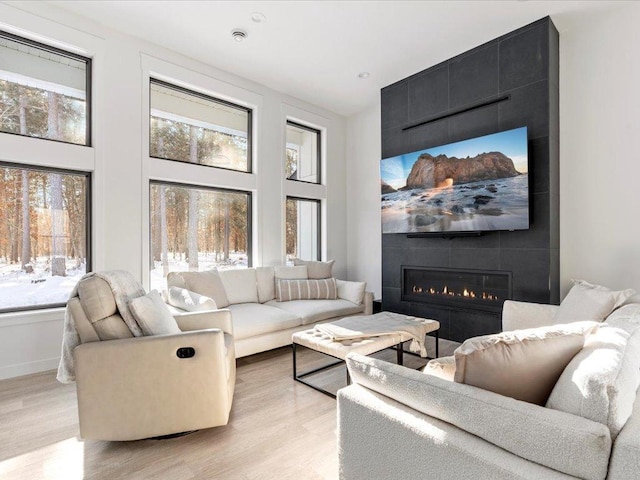 living area with a high ceiling, light wood-style floors, and a large fireplace