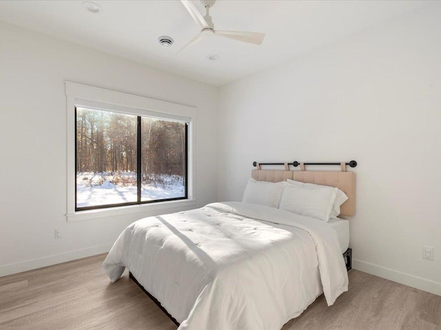 bedroom featuring ceiling fan, visible vents, baseboards, and light wood-style flooring