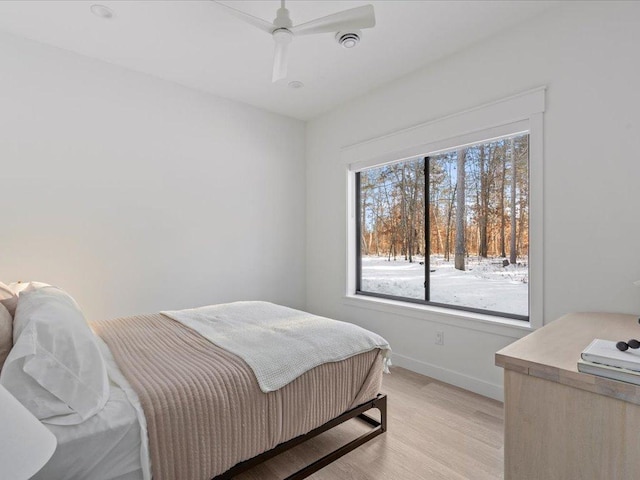 bedroom with baseboards, light wood-style floors, and a ceiling fan