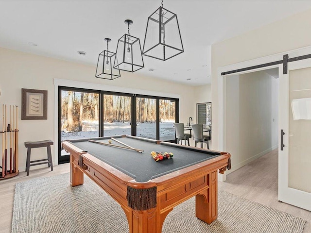 game room featuring light wood-style floors, a barn door, billiards, and baseboards