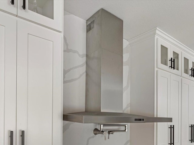 interior details featuring a textured ceiling and wall chimney exhaust hood