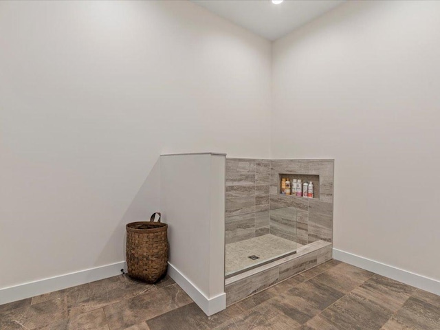 bathroom featuring baseboards and a tile shower