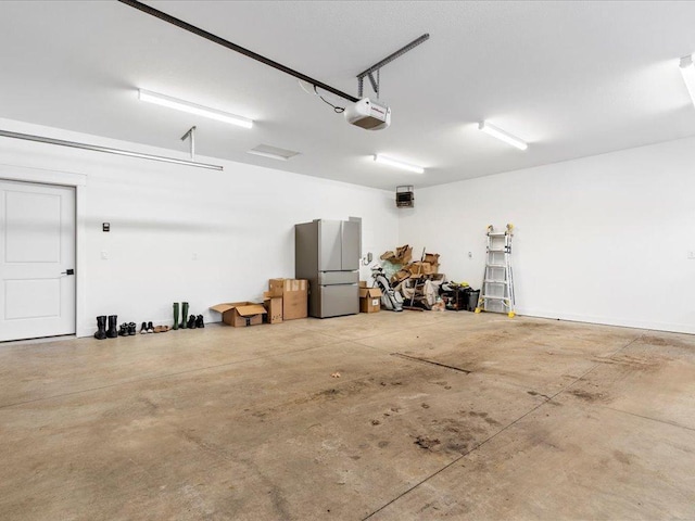 garage featuring a garage door opener and freestanding refrigerator