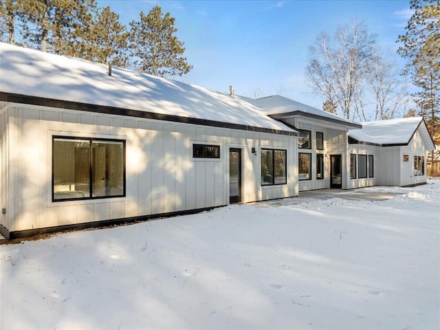 snow covered house with board and batten siding